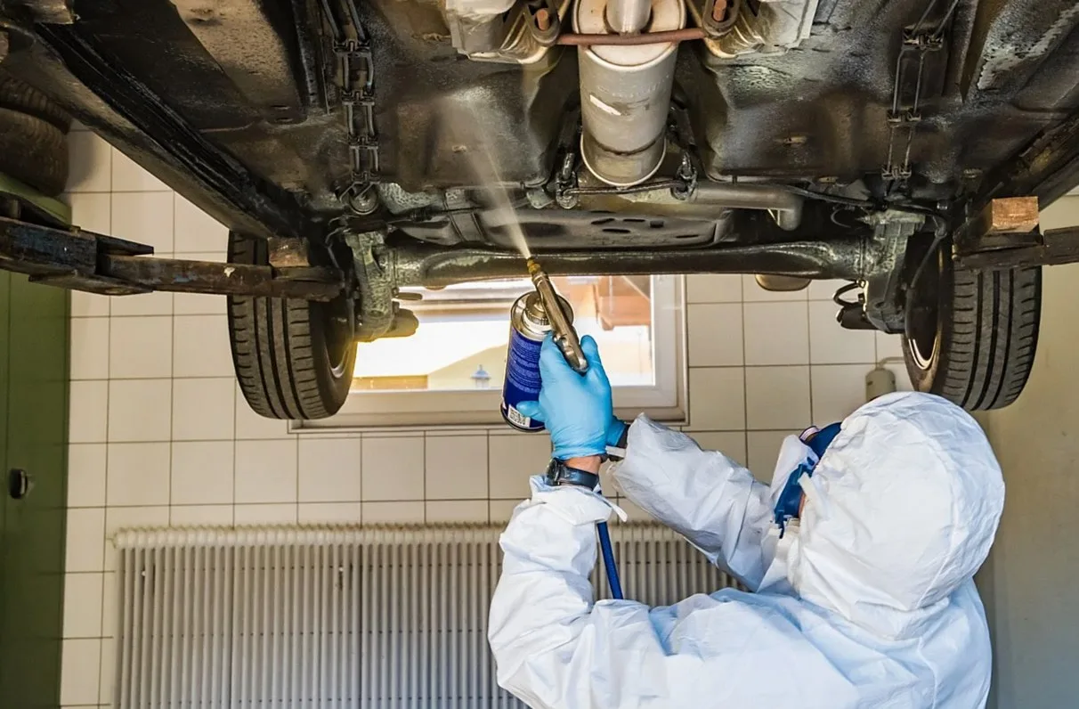 車の下回りに防錆処理を施す作業者